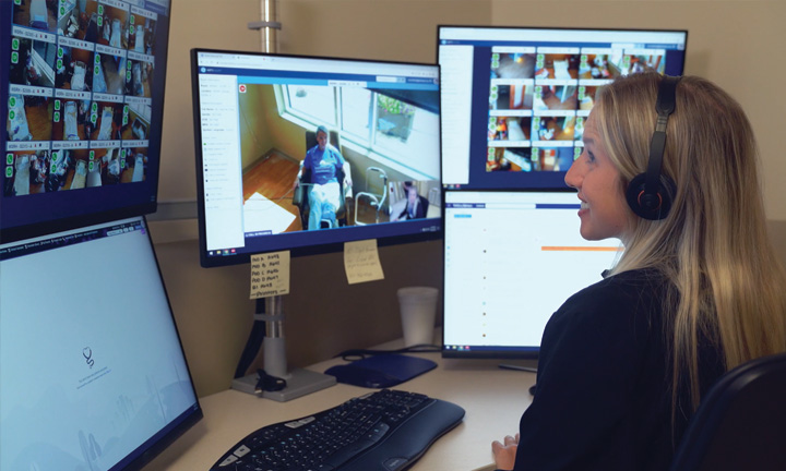 WellSpan Health virtual nurse wearing a headset at a multi-monitor workstation, video-connected to patient rooms